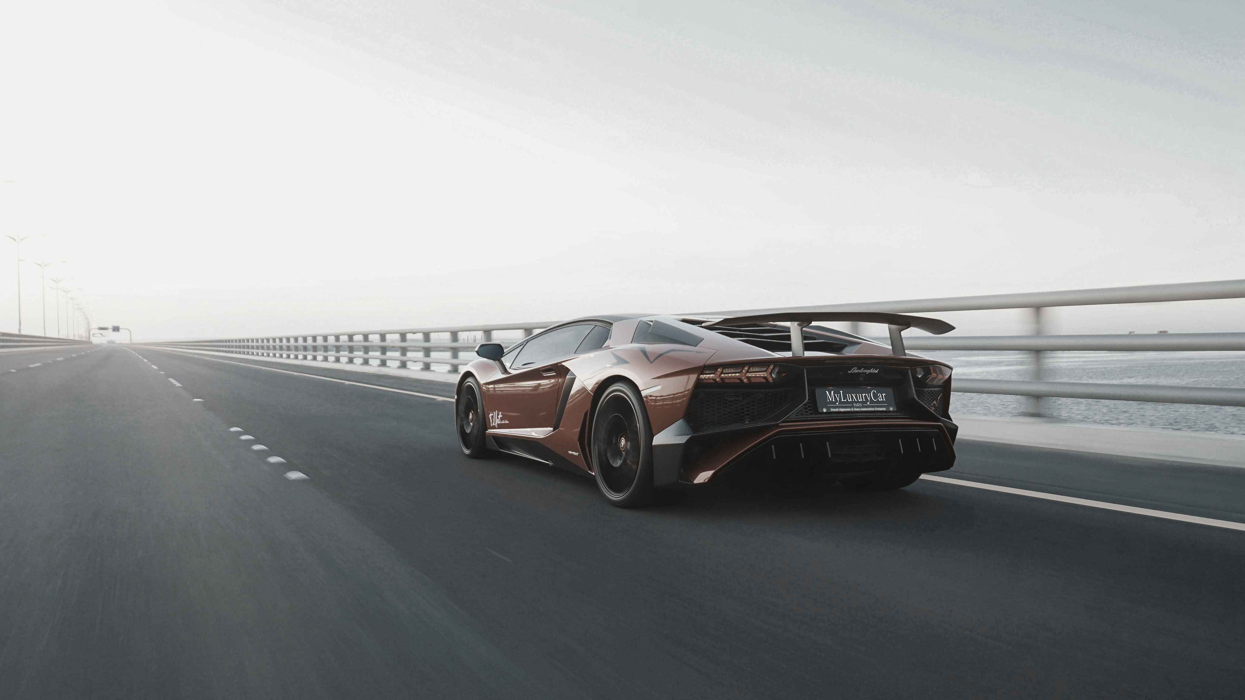 Lamborghini orange qui roule vite sur un pont vide